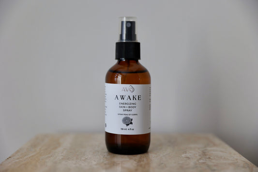 bottle facing forward is Avo's Awake Energizing skin and body spray made with Steam distilled organic essential oil blend with cold-pressed Lemon essential oil