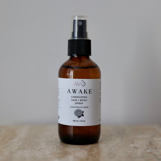 bottle facing forward is Avo's Awake Energizing skin and body spray made with Steam distilled organic essential oil blend with cold-pressed Lemon essential oil