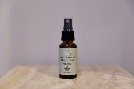 Bottle facing forward is Avo's mint and moist oral spray made with Water/eau, xylitol, organic gratissima (avocado) oil, steam distilled organic mentha piperita (peppermint) essential oil, syzygium aromaticum (clove) essential oil
